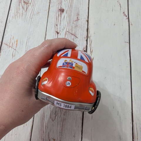 Puszka z flagą w kształcie samochodu z ruchomymi kołami